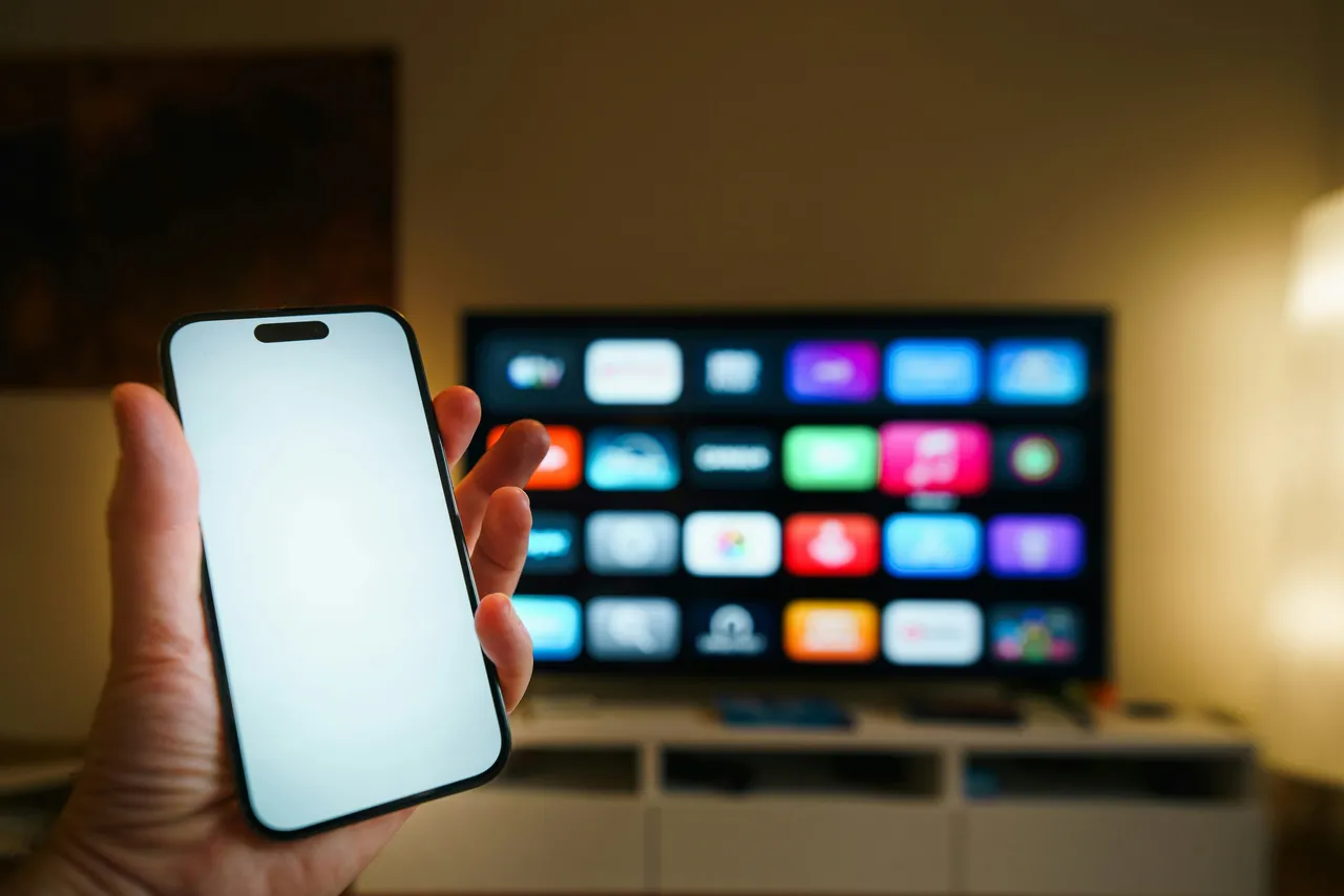 A phone held in front of a television in a living room