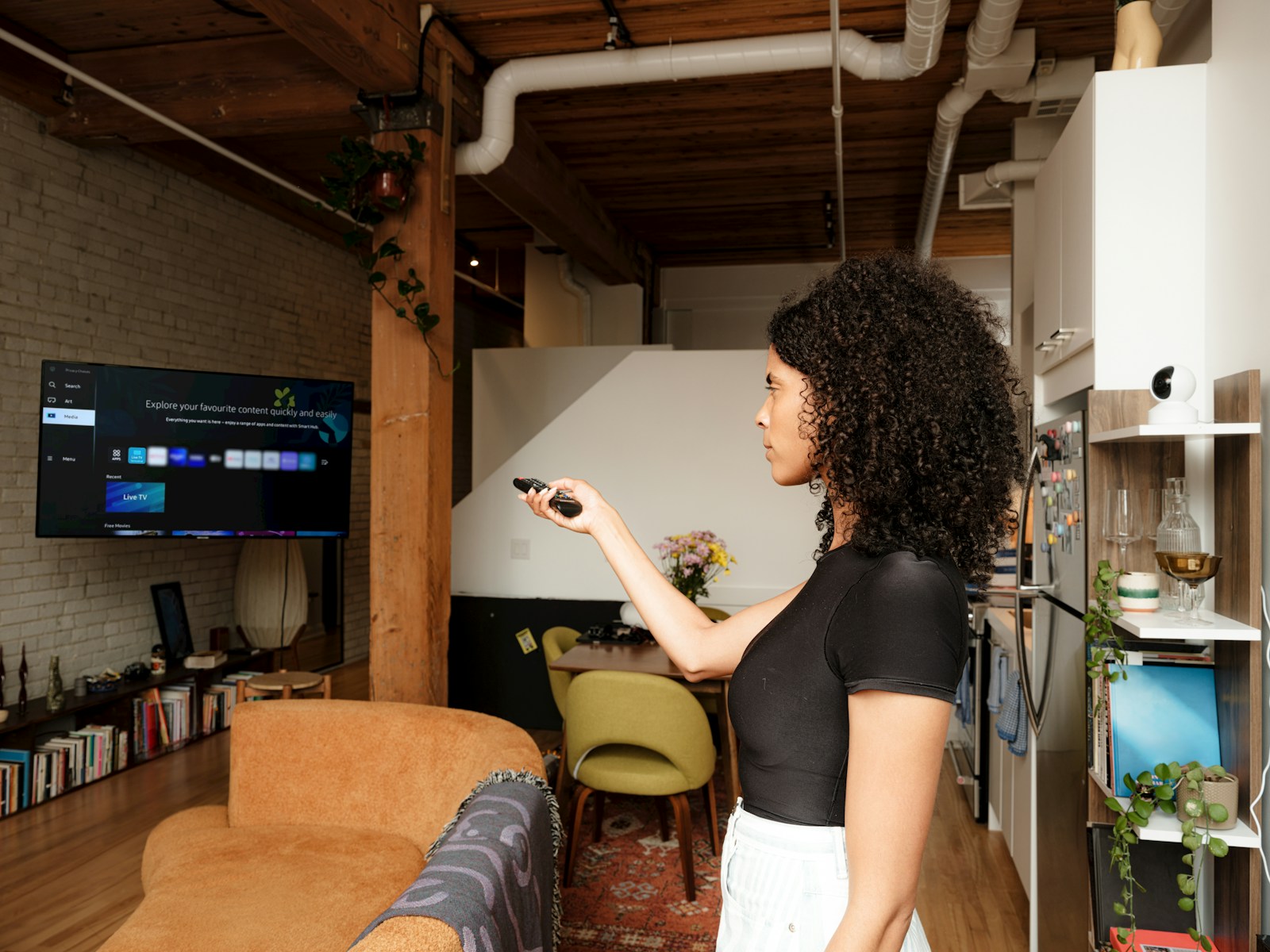 A woman in a living room holding a remote in front of a smart TV