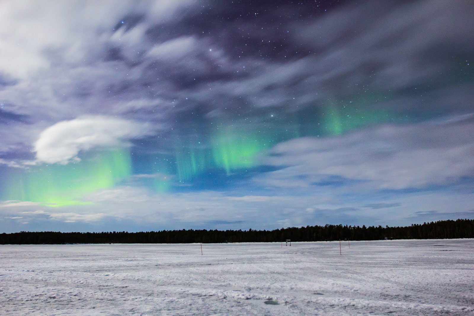 Aurora borealis over a Finnish lake at night, reflecting the northern lights on calm water